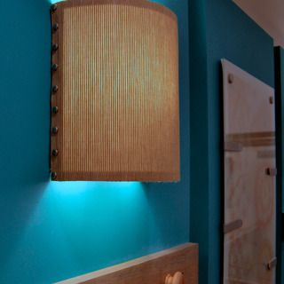 a bathroom with blue walls and wooden cabinetry, lights on the wall above it