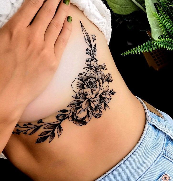 a woman's stomach with a flower tattoo on her side and the bottom part of her belly