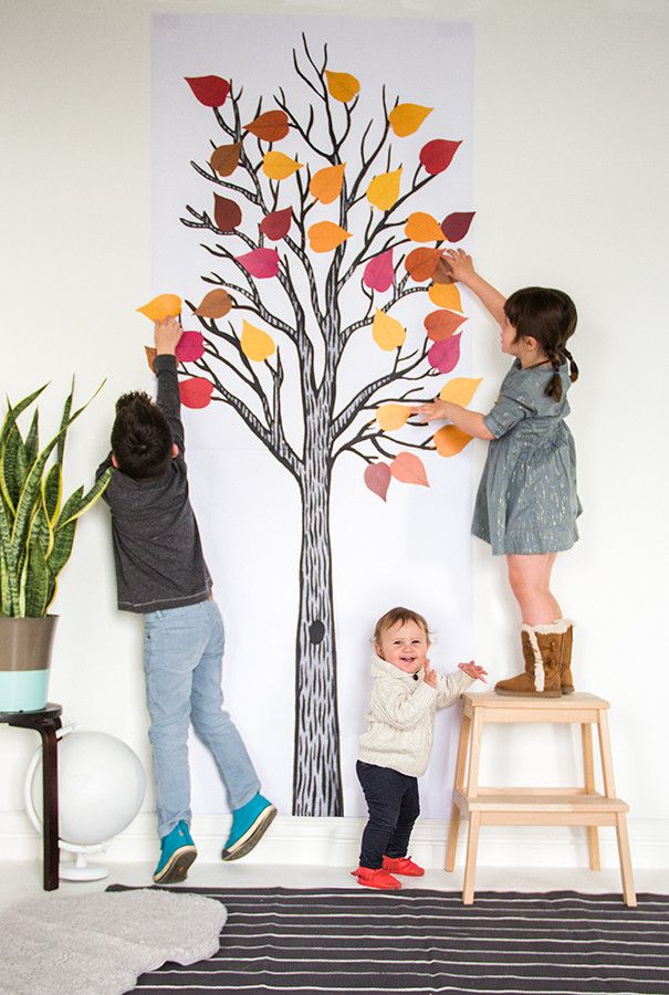 two children are playing with paper leaves on a tree