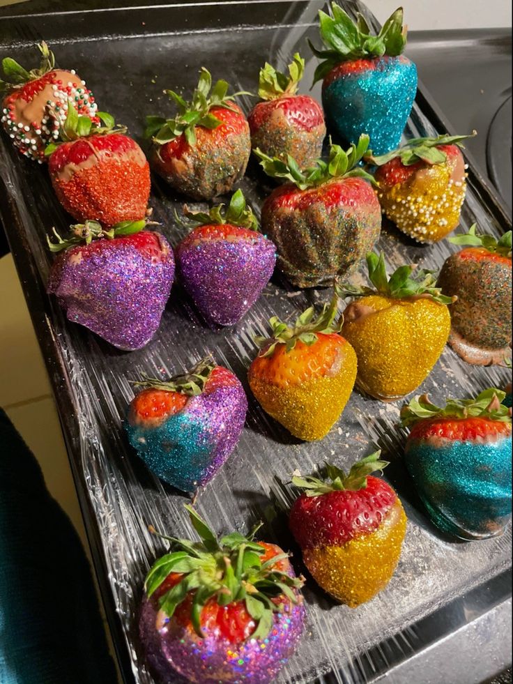 there are many different colored strawberries on the trays that have been decorated with sprinkles