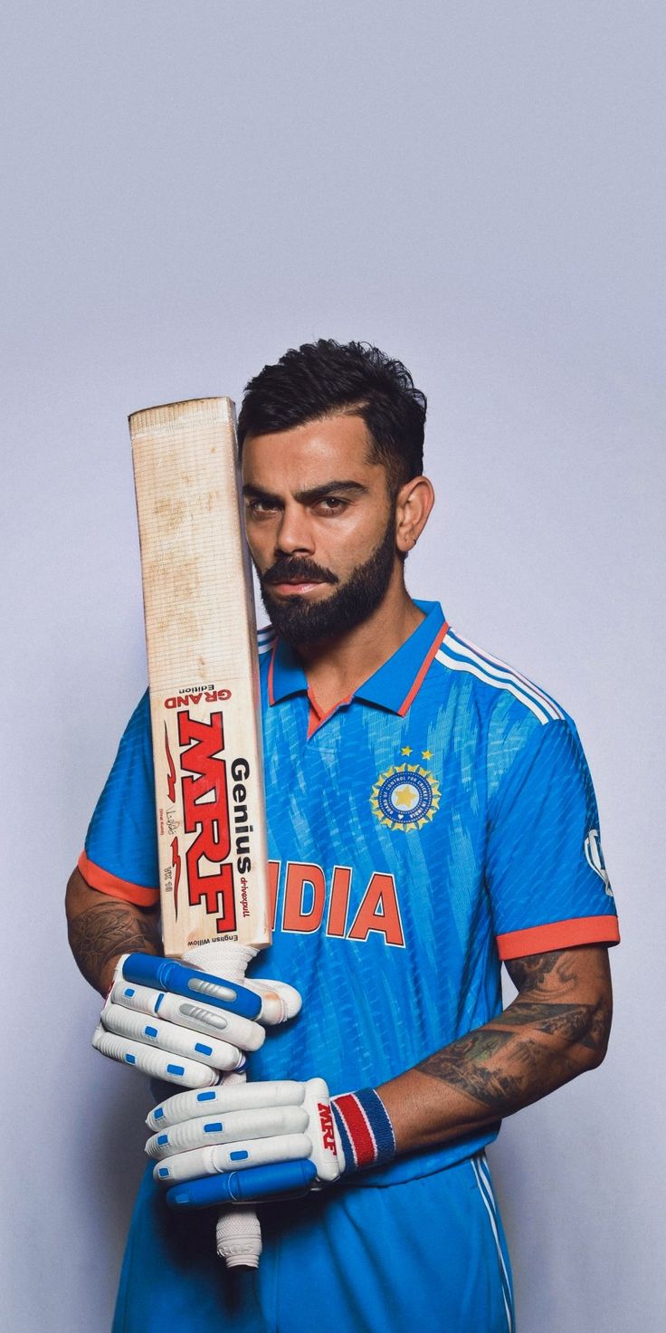 a man with a beard holding a cricket bat in his hands and looking at the camera