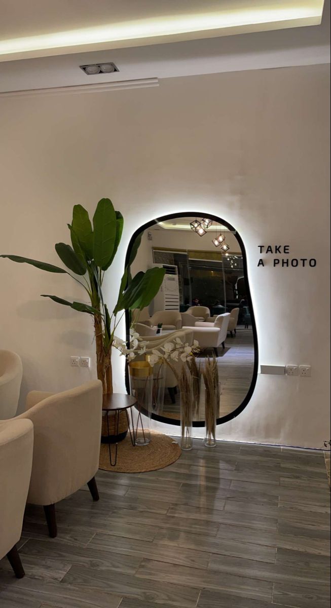 there are two chairs and a plant in front of a mirror that says take a photo