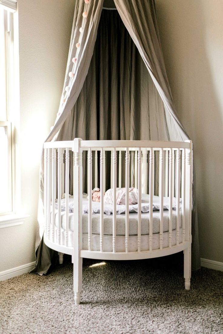 a white crib in the corner of a room next to a window with curtains