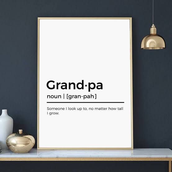 a white poster with the words grandpaa in black on it next to a vase and lamp