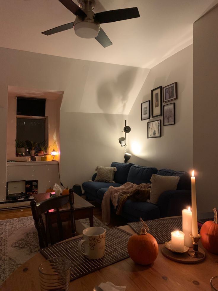 a living room filled with furniture next to a fire place and a ceiling fan on top of a wooden table