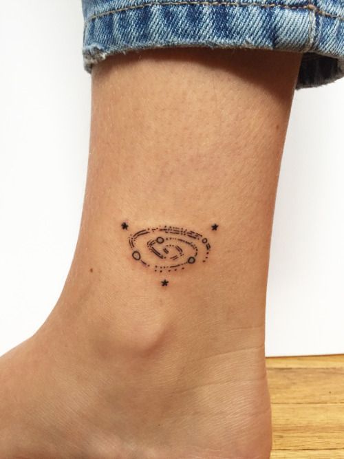 a woman's foot with a small space tattoo on the left side of her ankle