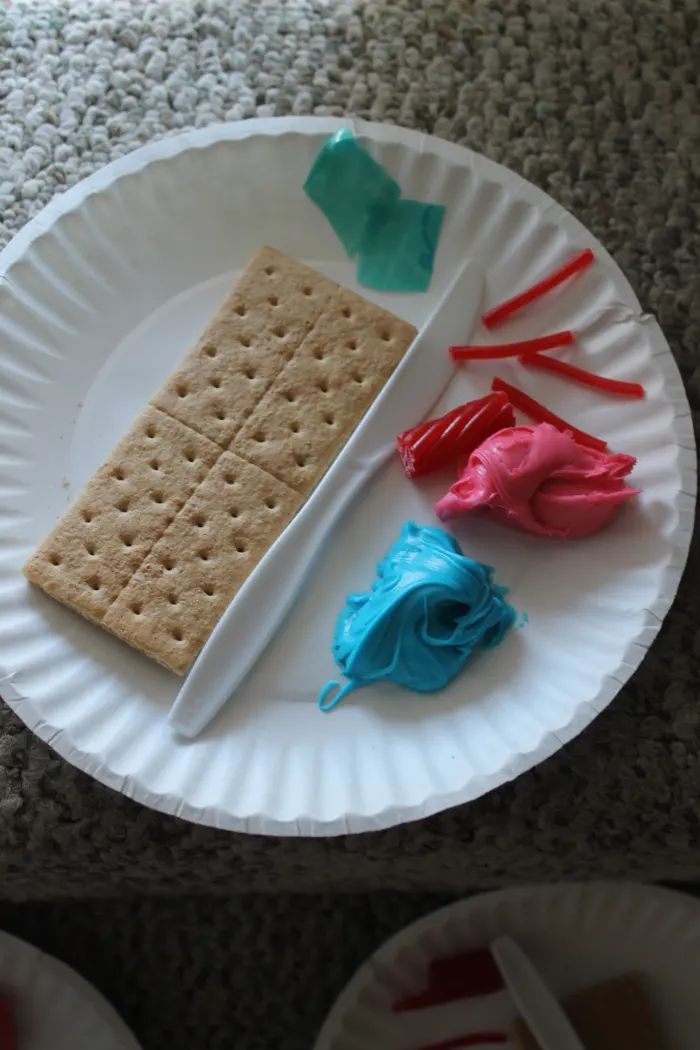 a paper plate with some crackers and blue, red, and white icing on it