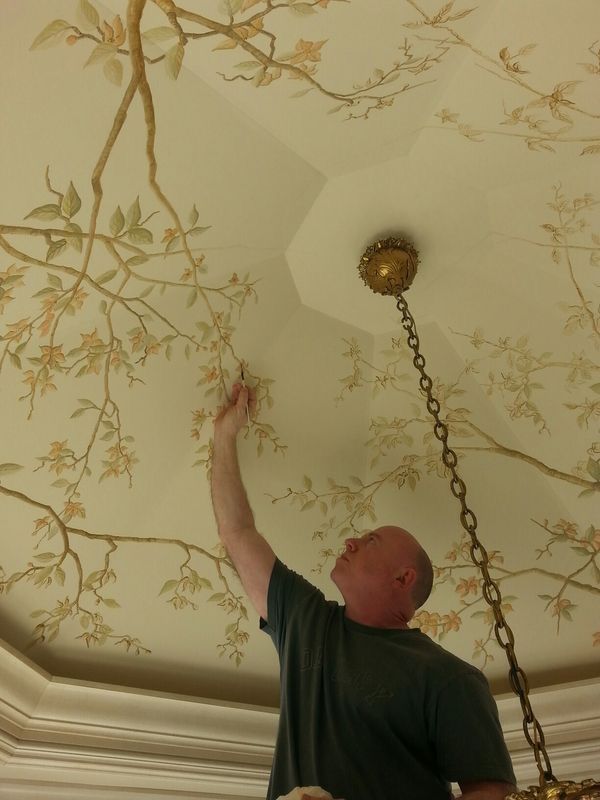 a man working on a ceiling with a chain hanging from it's center pole