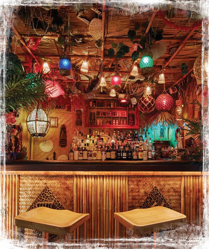 two wooden stools sitting in front of a bar filled with liquor bottles and plants