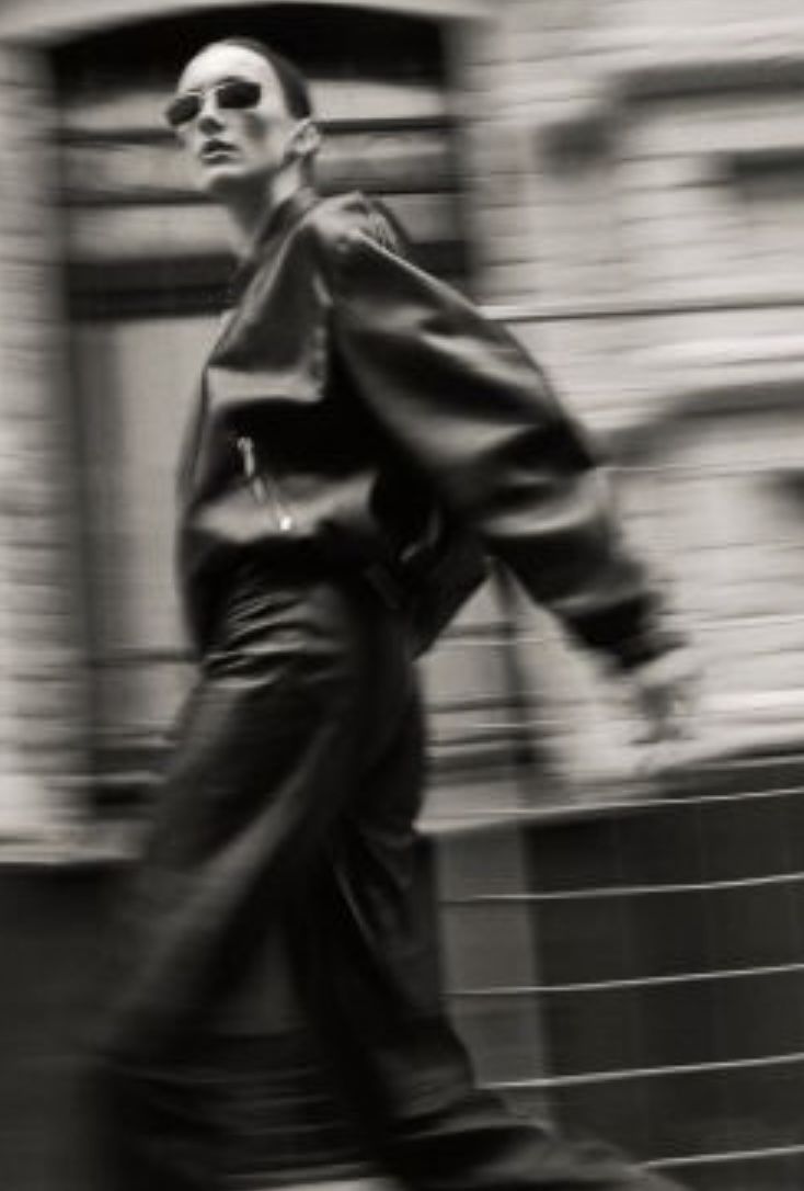 black and white photograph of a man walking down the street with his hand in his pocket