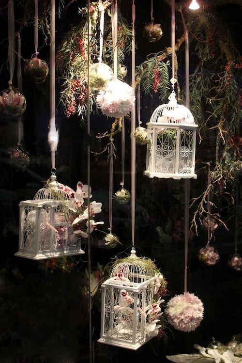 birdcages and flowers are hanging from the ceiling in front of a black background