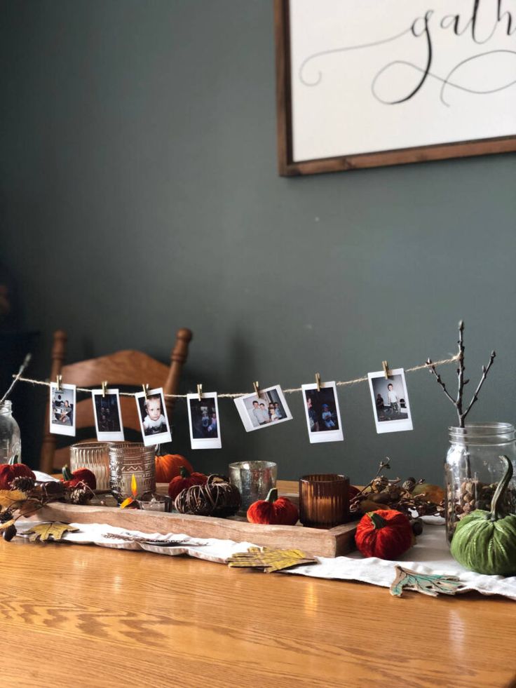 a wooden table topped with pictures and other items next to a framed photo on a string