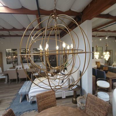 a chandelier hanging from the ceiling in a living room with chairs and tables