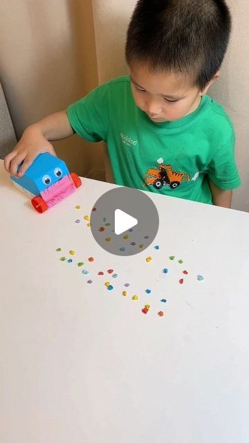 a young boy sitting at a table with a toy truck and sprinkles on it