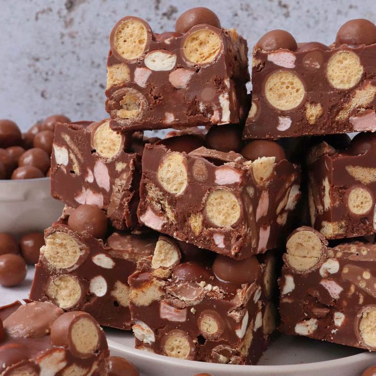 a white plate topped with brownies and marshmallows next to chocolate candies