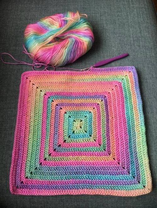 a crocheted square with yarn next to it