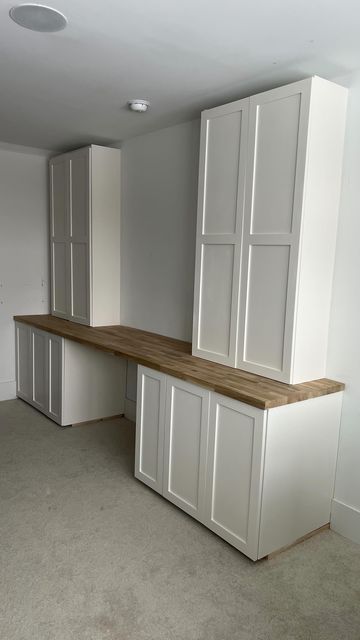 an empty room with white cabinets and wood counter tops