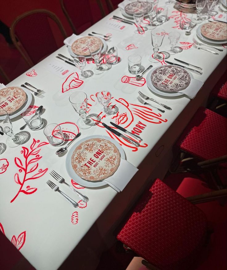 the table is set with red and white place mats, silverware, and utensils