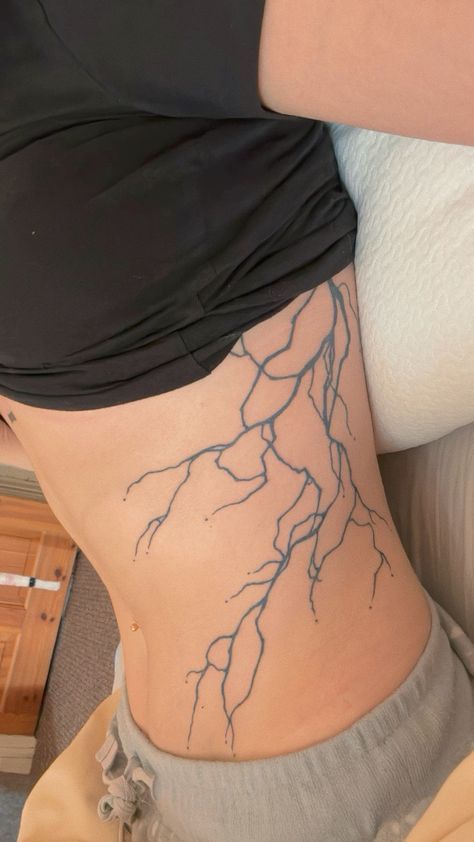 a woman's lower back with lightning tattoo on her stomach and the bottom part of her leg