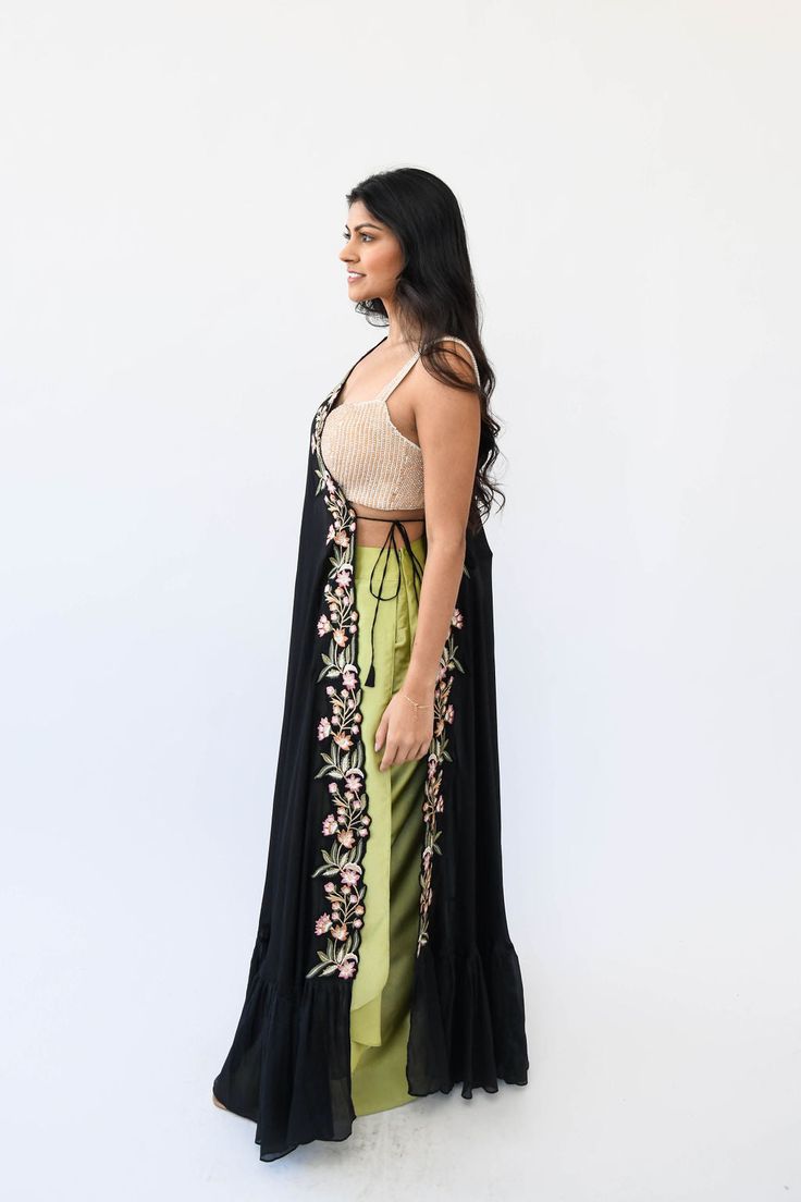 Crafted from luxurious chiffon, the Kiki Duster is an elegant piece of wearable art. The intricate, delicate resham thread work in a trio of subtle tones of pista, rose, and mango evoke subtlety and sophistication. It can be worn on either shoulder and is easily styled, making it the perfect accessory to your refined wardrobe. Features: Ties on the side Can be worn on either shoulder Resham thread work in colors rose, pista, and mango Base color: black Standard length is typically comfortable fo Bohemian Silk Sharara With Floral Embroidery, Bohemian Sharara With Floral Embroidery For Party, Bohemian Pre-draped Georgette Saree With Sheer Dupatta, Elegant Georgette Choli For Spring, Elegant Floral Embroidered Sharara For Summer, Elegant Floral Embroidery Sharara For Summer, Summer Georgette Saree With Floral Embroidery, Elegant Spring Choli With Resham Embroidery, Elegant Summer Sharara With Intricate Embroidery