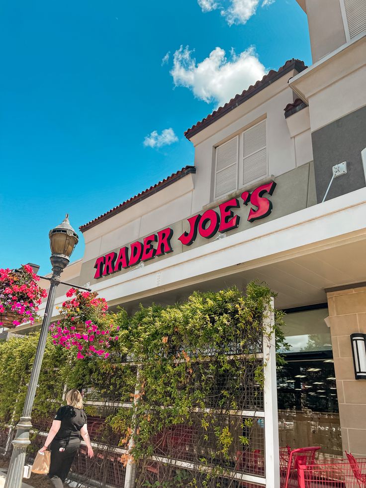 a woman walking past a trader joe's store