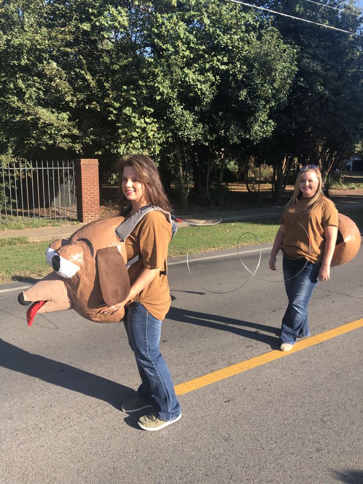 two people in costumes are walking down the street while one person is wearing a cow costume