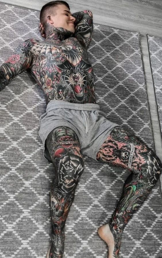 a man laying on top of a rug covered in tattoos