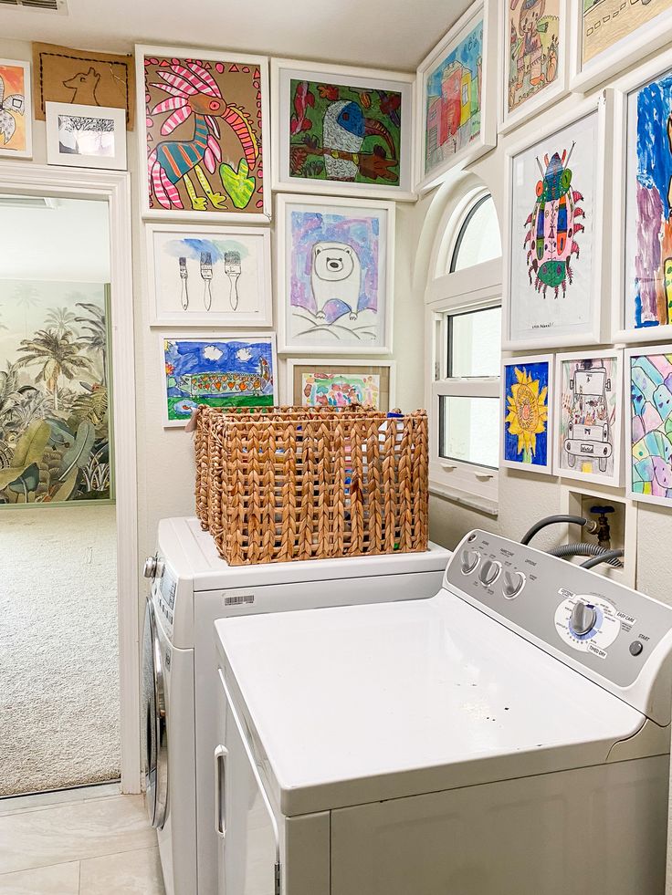 a washer and dryer in a laundry room with pictures on the wall behind it