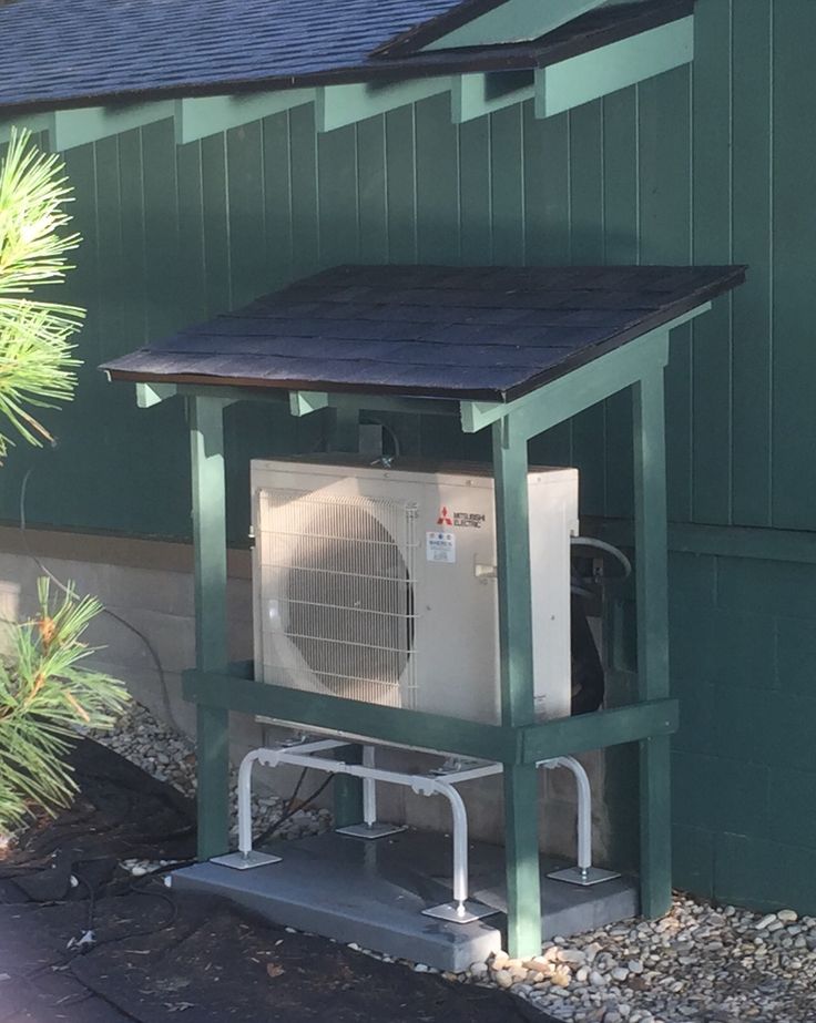 an air conditioner sitting in front of a green building