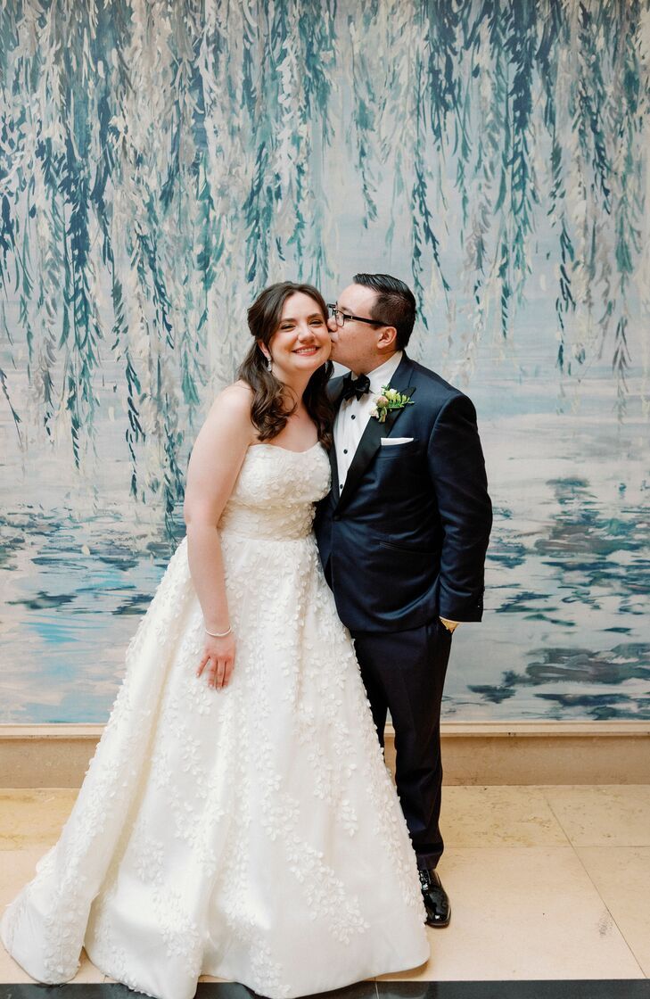 a bride and groom kissing in front of a painting