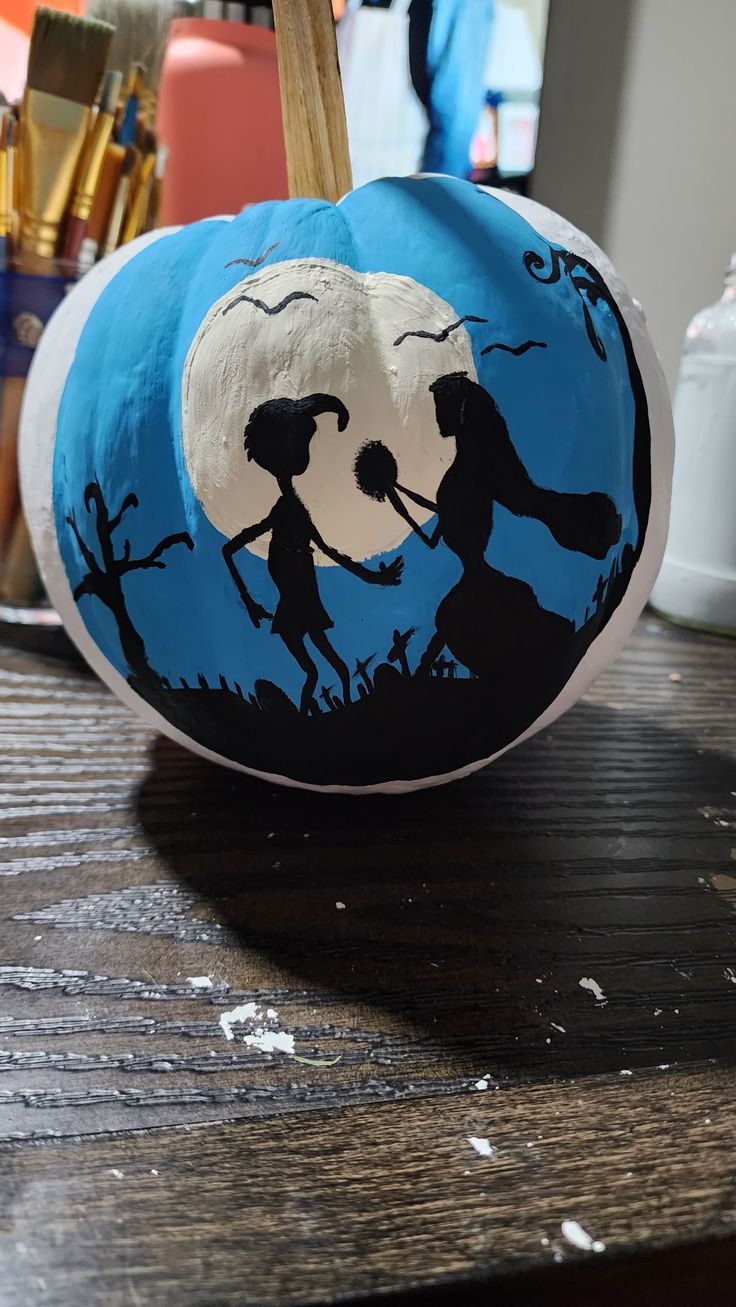 a painted pumpkin sitting on top of a wooden table