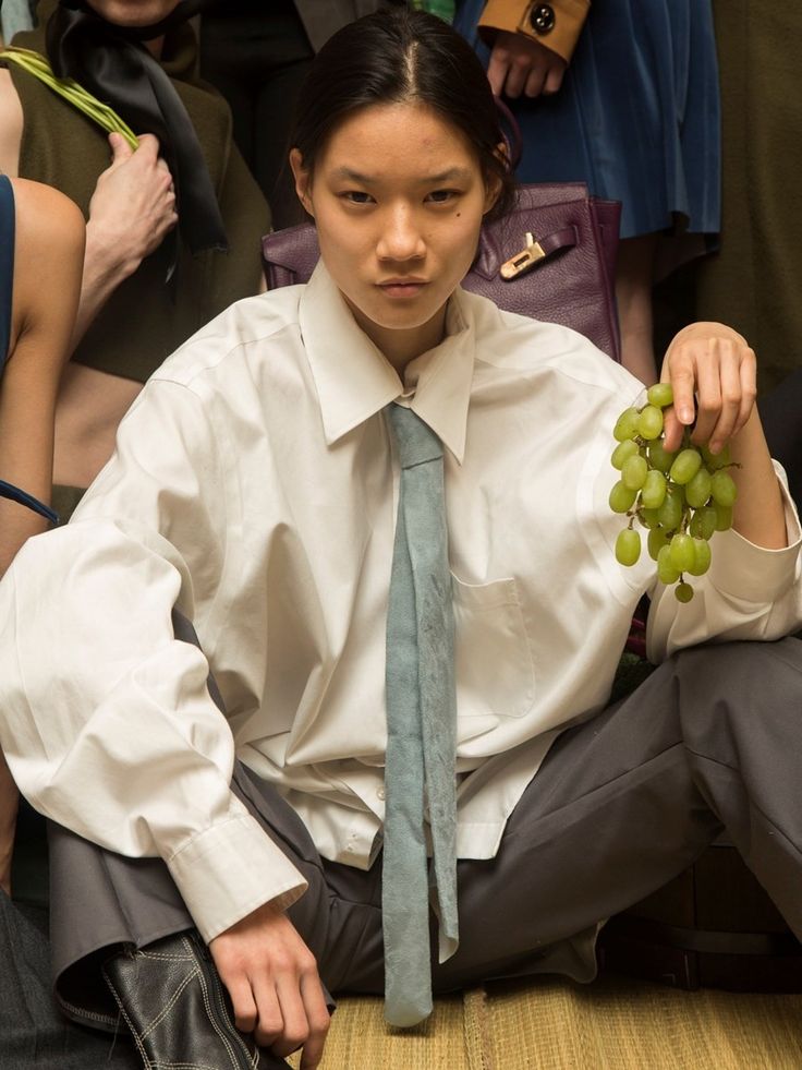 a woman sitting on the ground with grapes in her hand