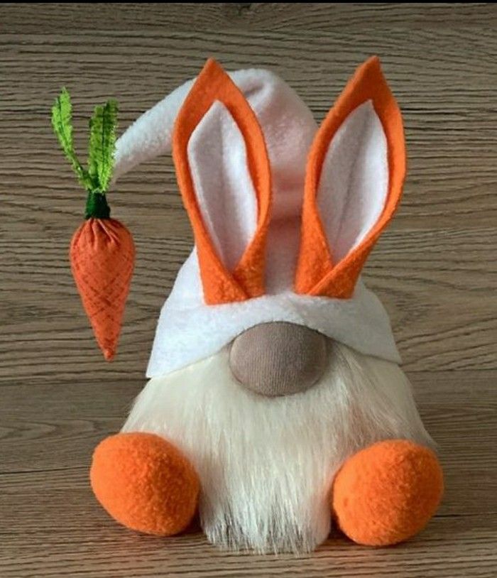 an orange and white stuffed animal with carrots on it's head sitting on a wooden surface