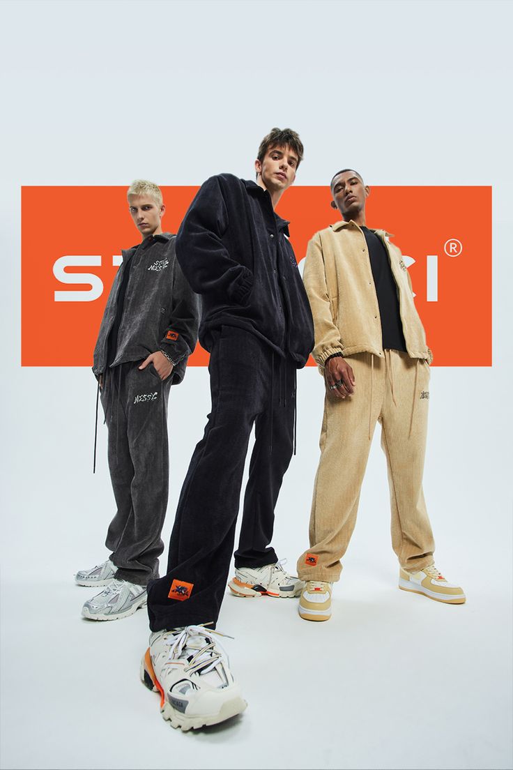 three young men standing next to each other in front of an orange and white sign