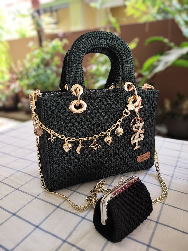 a black purse sitting on top of a table next to a handbag and chain