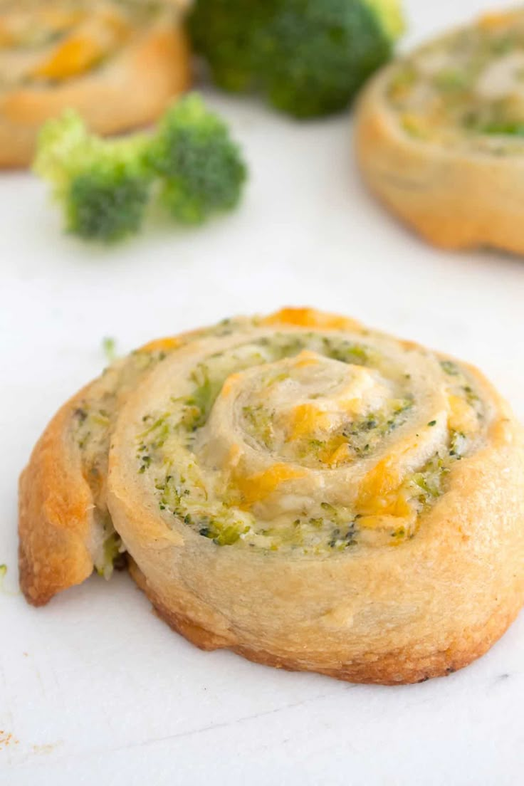 some broccoli and cheese cookies on a white surface with other food items in the background