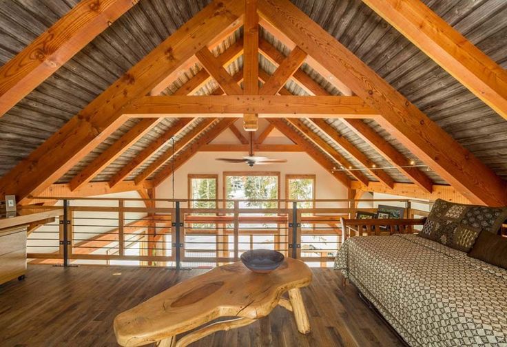 a living room filled with furniture and wooden beams on top of a roof covered in wood