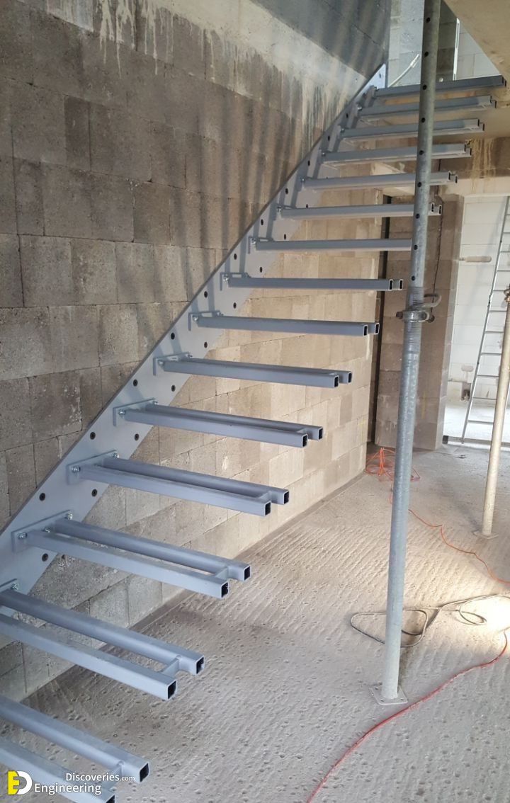 a set of metal stairs next to a brick wall in an empty room with concrete flooring