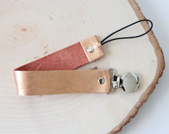 two leather keychains sitting on top of a piece of wood