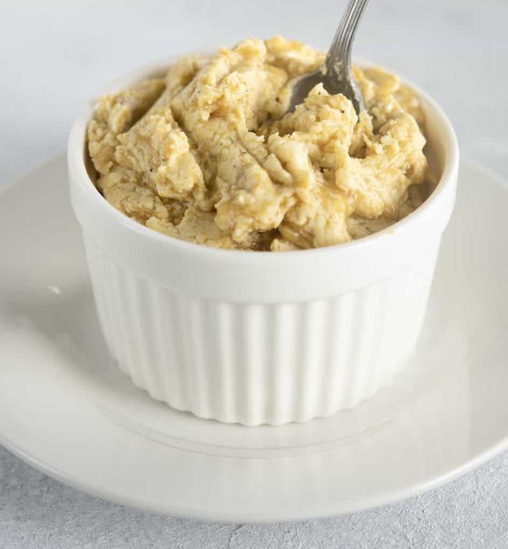 a white bowl filled with mashed potatoes on top of a plate next to a fork