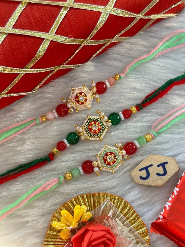 some beads are laying on top of a white fur surface and a red rose is placed next to it