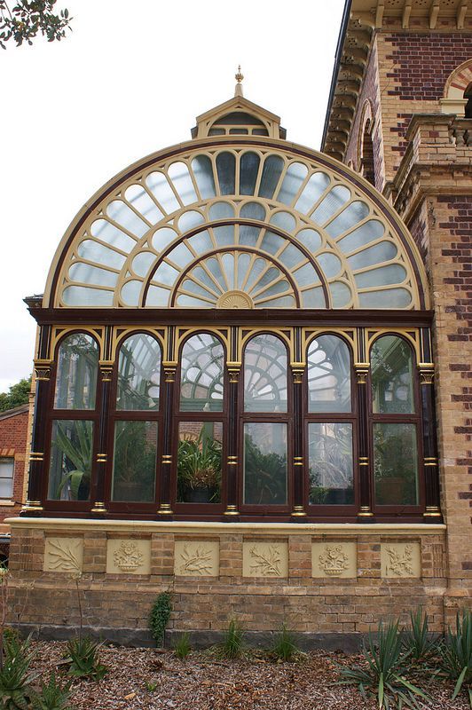 an ornate building with many windows and plants in the window sill, near a brick wall