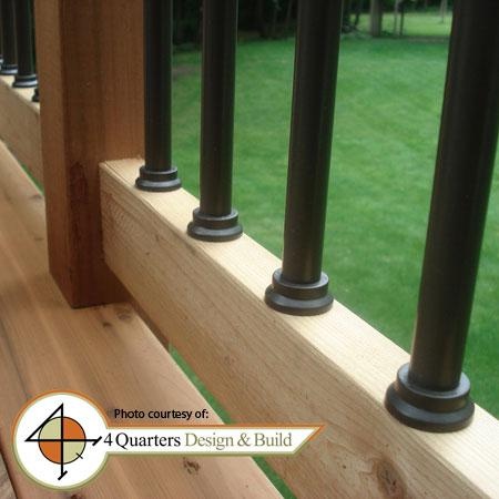 a wooden deck with metal posts and railings in front of a grassy lawn area