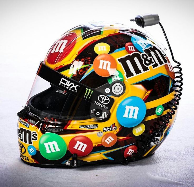 a helmet with many stickers on it sitting on top of a white surface next to a microphone