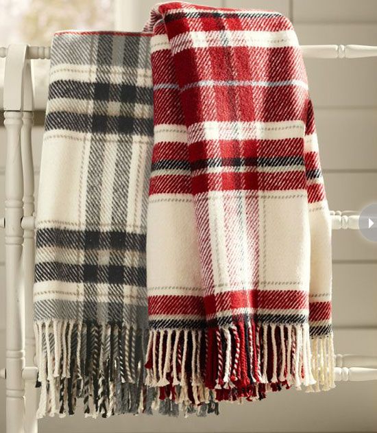 a red, white and black plaid blanket sitting on top of a chair next to a window