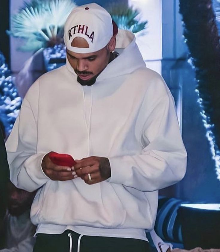 a man in a white hoodie looking at his cell phone