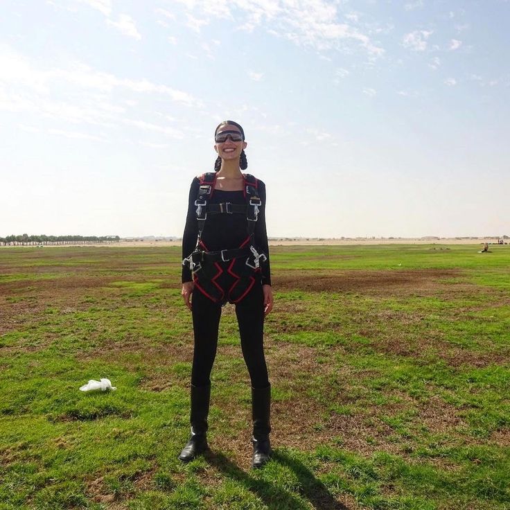 a woman standing in the middle of a field with her face covered by an eye patch