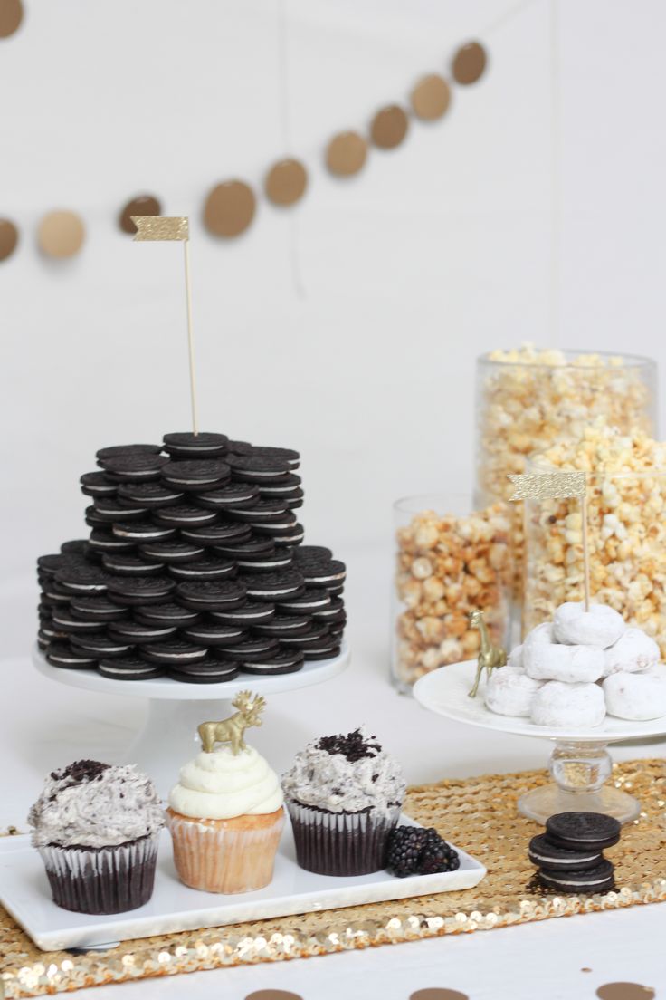 a table topped with lots of cupcakes next to a cake on top of a plate