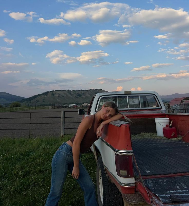 a woman leaning on the back of a pickup truck