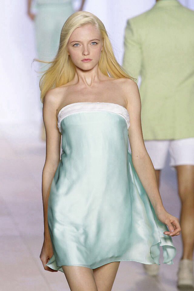 a woman walking down a runway in a green dress